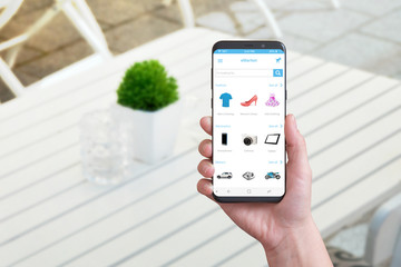 Poster - Online shopping app on smart phone with round edges. Coffee shop in background.