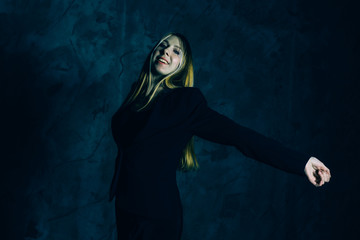 Attractive pretty young model posing against a dark studio background with copy space looking. Atomic blonde woman stands with widely spread arms. Comic style of color