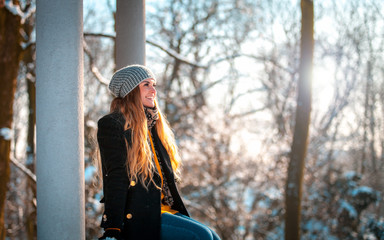 Wall Mural - Smiling young woman during walk in the winter park at sunny day