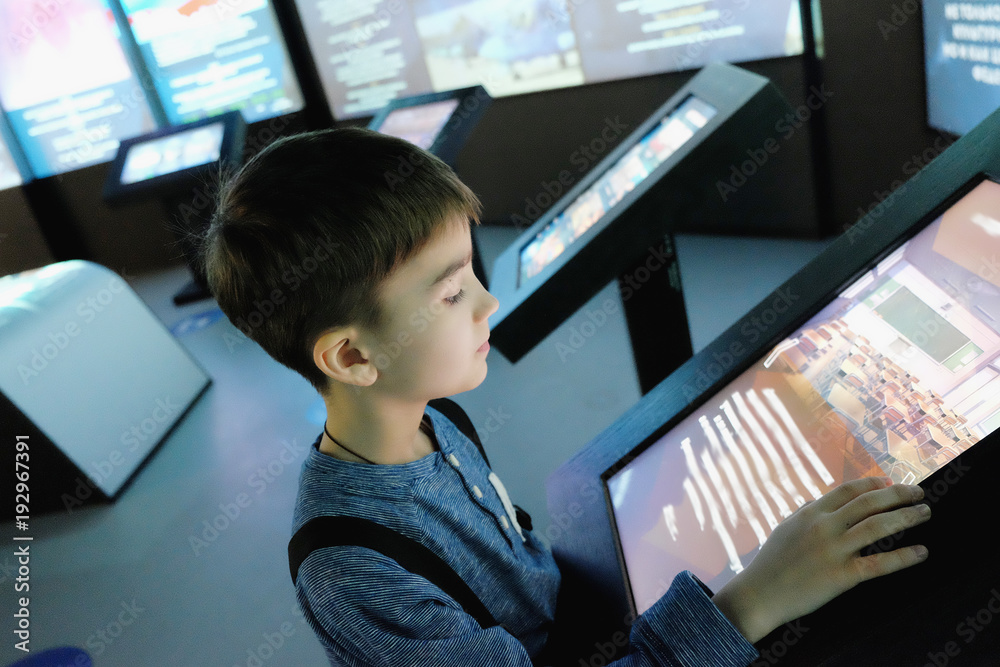 child examines the touchscreen in the interactive Museum - obrazy, fototapety, plakaty 