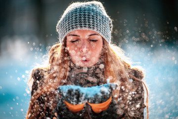 Winter woman blowing snow outdoor at sunny day, flying snowflakes