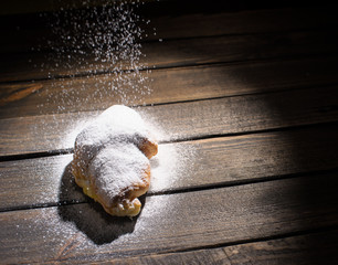 Wall Mural - croissant on wooden desk with falling powdered sugar