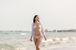 © Kzenon - Woman in bikini walking down the beach in her summer vacation along the water