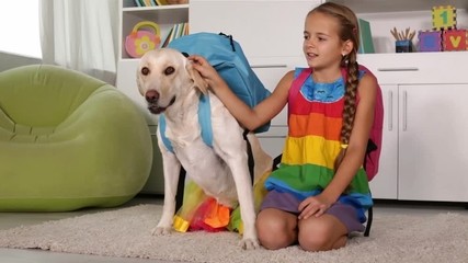 girl playing with dog - with scghoolbags on their backs, ready for school