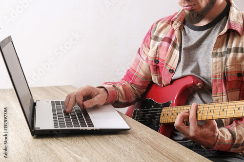 Cuadros en Lienzo Casually dressed beard young man with guitar playing songs in the room at home