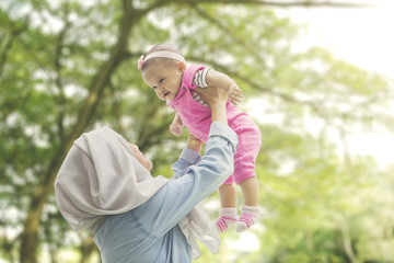 Muslim mother playing with daughter at park