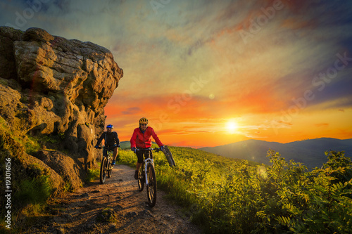 Mountain Biking Women And Man Riding On Bikes At Sunset