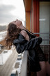 © Iulia - Young sexy woman in a black fur coat and lingerie standing on balcony