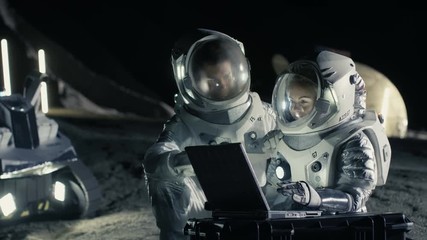 Wall Mural - Two Astronauts Wearing Space Suits Work on a Laptop, Exploring Newly Discovered Planet, Send Communicating Signal to Earth. Space Travel, Exploration and Colonization Concept. 