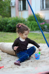 Little kid girl playing in a children sandbox.