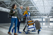 © Yakobchuk Olena - Smiling air passengers entering to the airport. They are pushing the cart with baggage