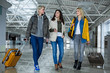 © Yakobchuk Olena - Recreation concept. Full length of three girls with baggage walking through airport and communicating