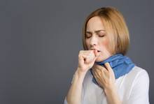 Health Concept. Portrait Of Displeased Girl In Scarf Holding One Hand Near Her Mouth And Coughing. Copy Space In Left Side. Isolated On Background