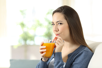 Wall Mural - Woman drinking orange juice with a straw