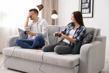 Canvas Print - Young couple playing video games at home