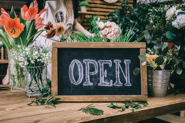 Poster - Wooden table with floral arrangements and blackboard saying Open in flower shop. 