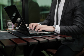 Poster - Young Asian businessman working with a laptop in a coffee shop.
