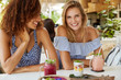 © WHstudio Leushin N - Horizontal shot of females best friends with broad smile sit together at cafe table, share impressions about summer holidays, drink tasty smoothie and eat exotic dish. People, lifestyle, friendship