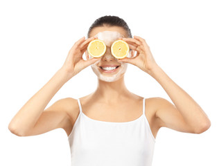 Wall Mural - Beautiful young woman with facial mask and slices of ripe lemon on white background