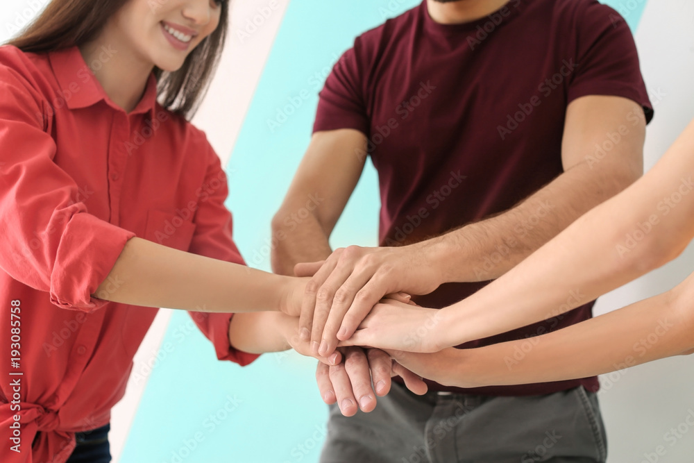 Young people putting hands together indoors. Unity concept
