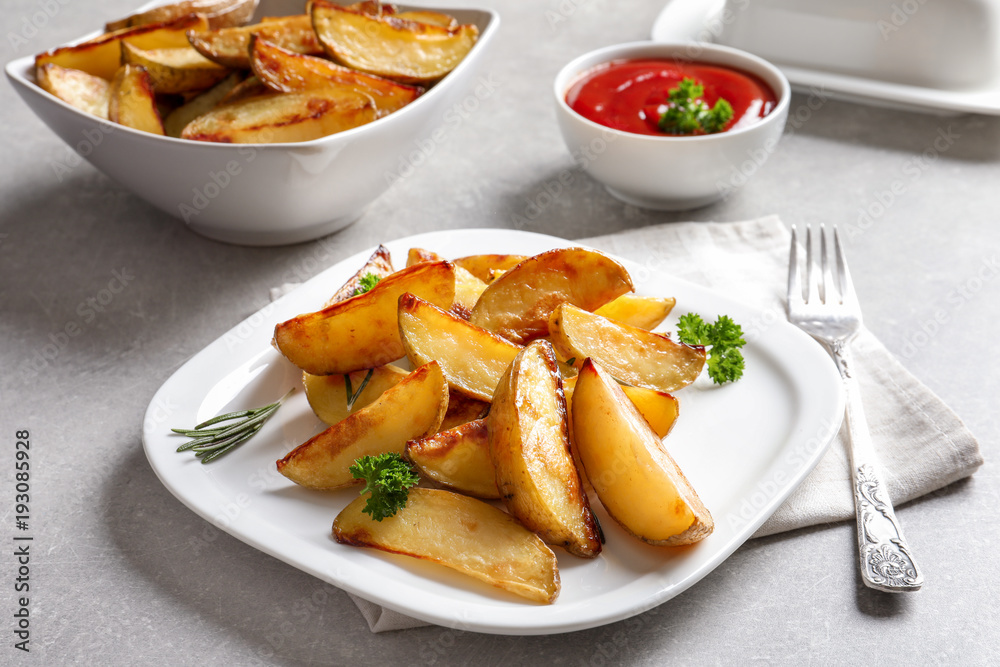 Plate with delicious baked potato wedges on table
