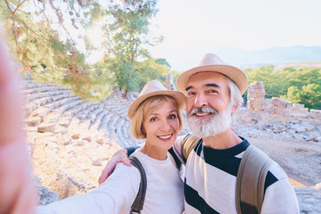 Tourism and technology. Traveling senior couple taking selfie together against ancient sightseeing background.