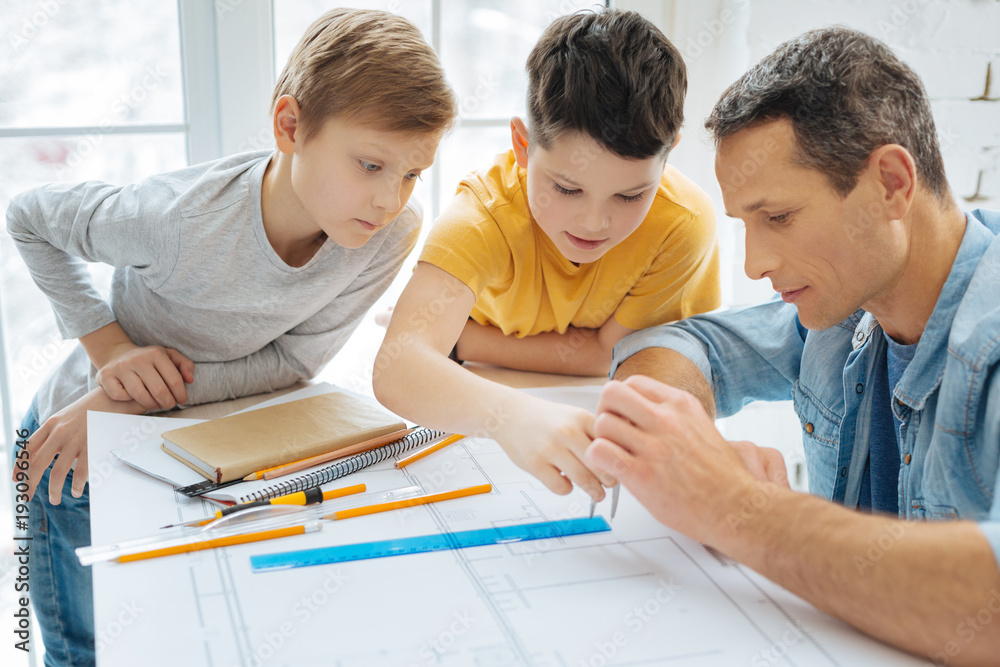 Easy lesson. Curious pre-teen boys leaning over their fathers work desk ...