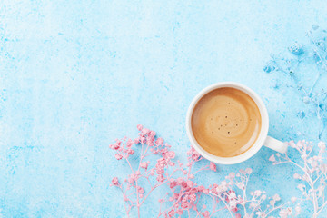 Morning cup of coffee and colorful flowers on blue pastel table top view. Flat lay style. Creative breakfast for Woman day.