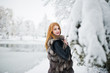 © AS Photo Family - Red haired girl in fur coat walking at winter snowy park.