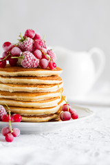 Wall Mural - Stack of pancakes with raspberry, red currant, cream and honey on white table cloth