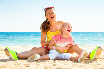 Wall Mural - smiling trendy mother and daughter on seashore having fun time