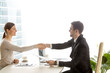 © fizkes - Male human resources manager holding resume and welcoming with handshake female job candidate in company office. Business partners agreeing with terms of contract. Successful negotiation. Side view