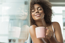 Portrait Of Cheerful African Woman Expressing Pleasure While Drinking Cup Of Delicious Beverage In Room