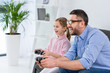 © LIGHTFIELD STUDIOS - side view of happy daughter and father playing video game together at home