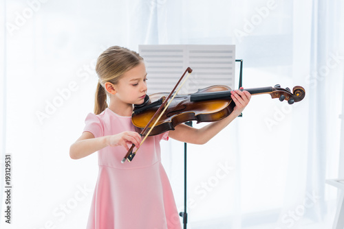 Fotomural cute little child in pink dress playing violin at home