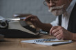 © LIGHTFIELD STUDIOS - close-up shot of senior writer rewriting manuscript with typing machine
