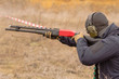 Male training with pump action shotgun  outdoors in field. 