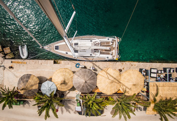 Wall Mural - Sailing boat on embankment with palms and restaurant, bar