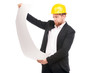 © Mediaphotos - Portrait of architect wearing suit and yellow hardhat holding project plan on white background