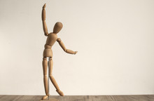 Wooden Dummy Toy Poses On White Wall Background