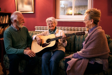 Wall Mural - Group of senior friends playing guitar and having fun at nursing home