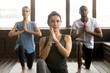 © fizkes - Group of young afro american and caucasian sporty people practicing yoga lesson with instructor standing in anjaneyasana exercise, Horse rider pose, working out, indoor close up, studio