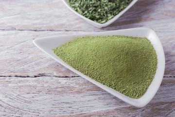 Wall Mural - powder and moringa leaves in bowl on rustic wooden background