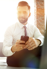 Canvas Print - businessman holding a smartphone and looking at the camera