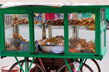 Traditional street food of Sri Lanka - chickpea with coconut, small fried fish, vegetable patties, donuts on a mobile cart.