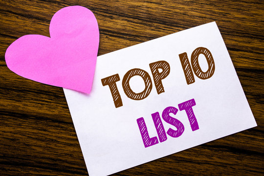 Conceptual hand writing text showing Top 10 Ten List. Concept for Success ten list written on sticky note paper, wooden wood background. With pink heart meaning love adoration.
