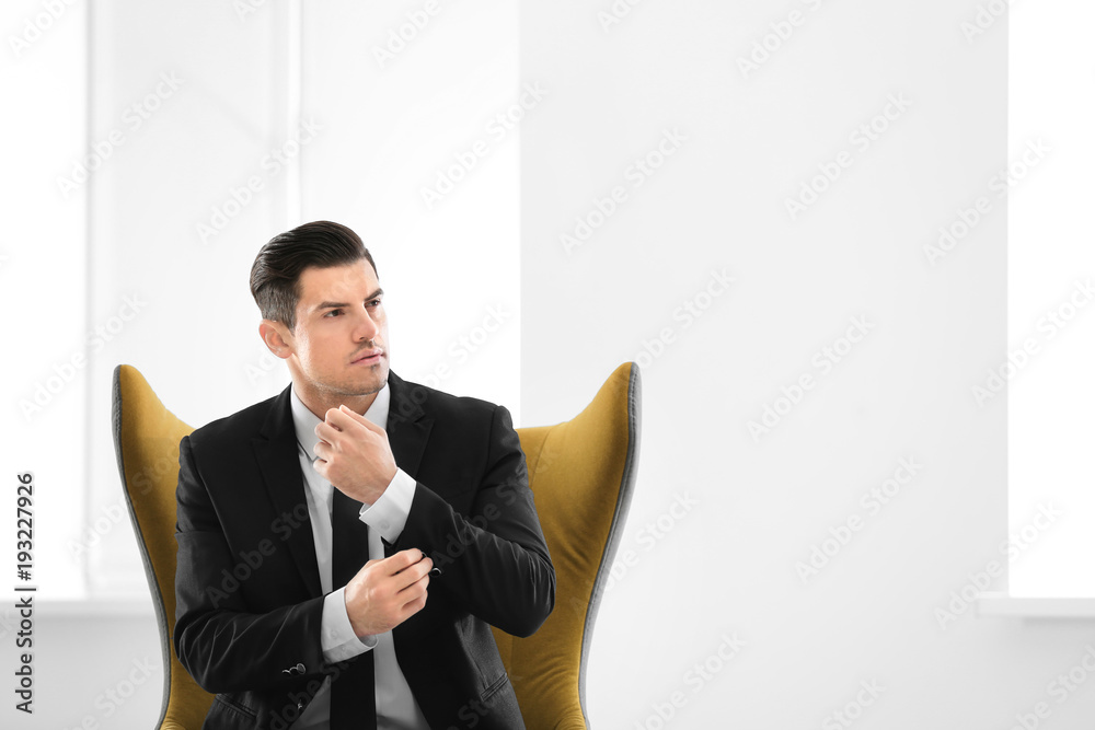 Handsome businessman sitting in comfortable armchair indoors