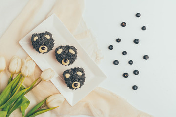 Wall Mural - top view of gourmet cupcakes in shape of bears, fresh blueberries and tulip flowers
