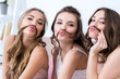 © LIGHTFIELD STUDIOS - beautiful happy girlfriends in pajamas holding hair as moustaches and smiling at camera