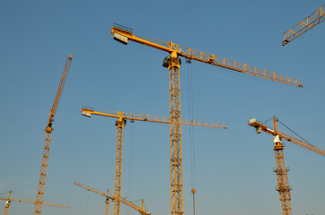 multiple tower cranes at the construction site with blue sky background